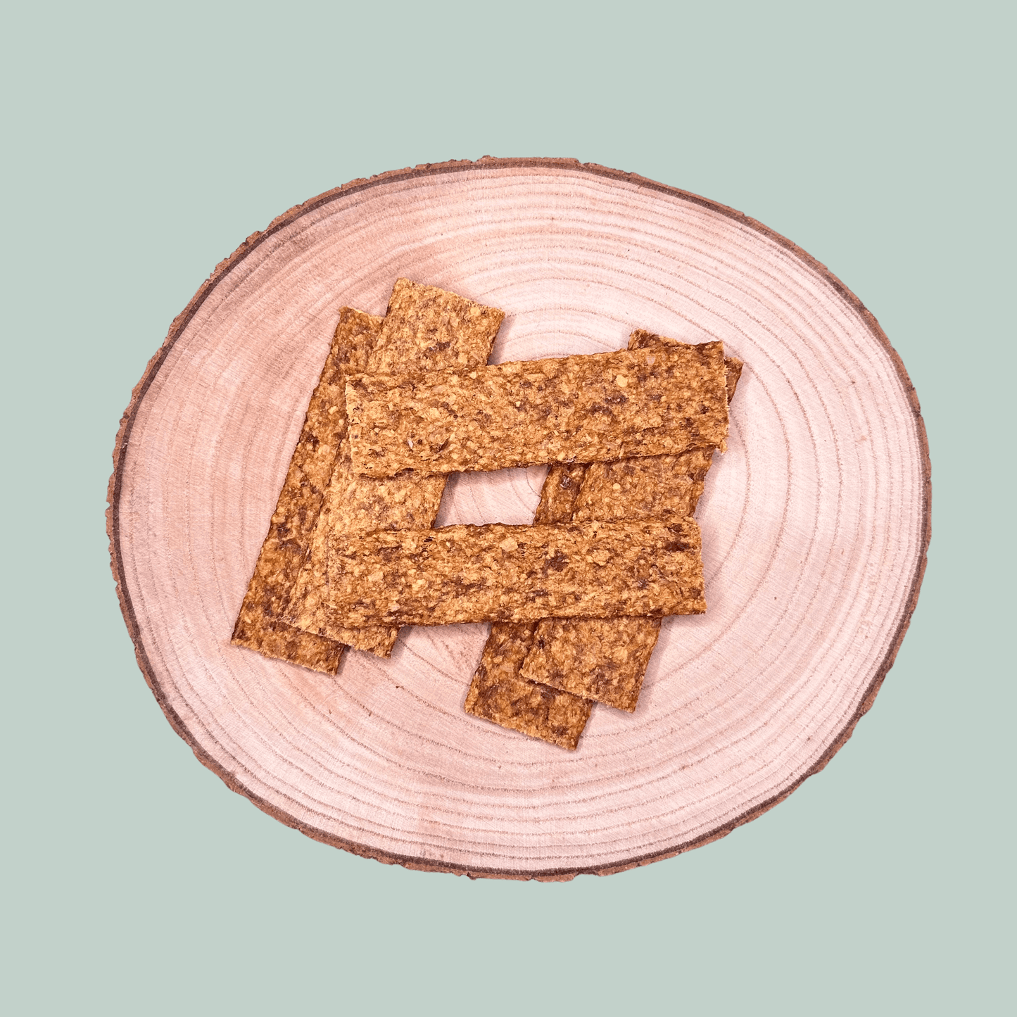 Pure meat strip dog treats on a wooden plate and jade green background