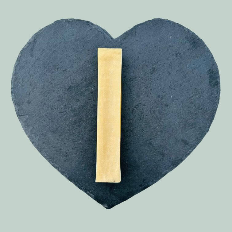 Single extra large yak cheese bar for dogs on a slate plate and jade green background