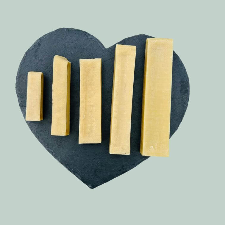 Full range of yak bars for dogs on a slate plate and jade green background