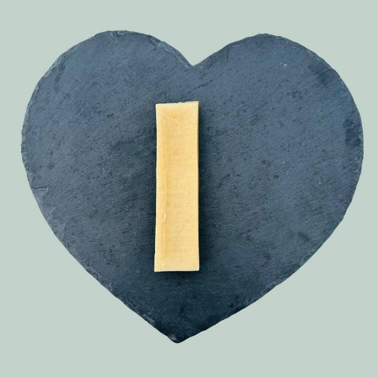 Single large yak cheese bar for dogs on a slate plate and jade green background