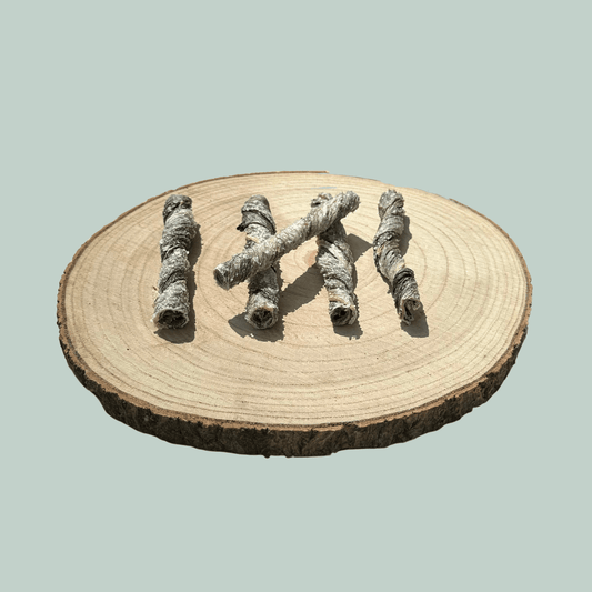 Side view of 5 dried salmon skin dog treats on a natural wooden slice plate against a jade green background