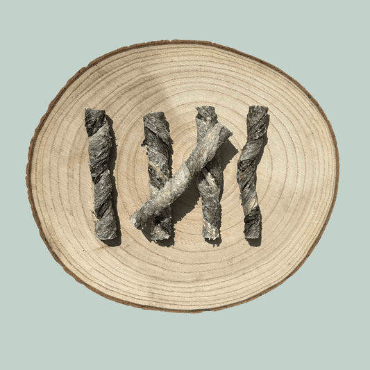 5 dried salmon skin dog treats on a natural wooden slice plate against a jade green background