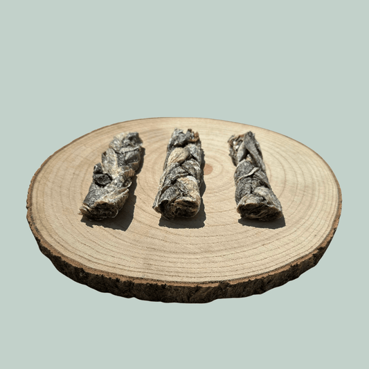 Side view of 3 natural cod skin braid dog chews on a wooden slice plate against a jade green background