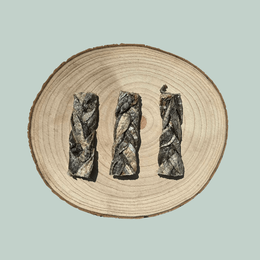3 natural cod skin braid dog chews on a wooden slice plate against a jade green background