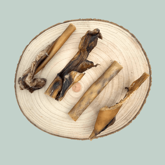 4 slices of venison skin chews for dogs on a wooden plate against a jade green background.