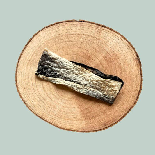 Piece of dried fish skin dog chew on a wooden plate