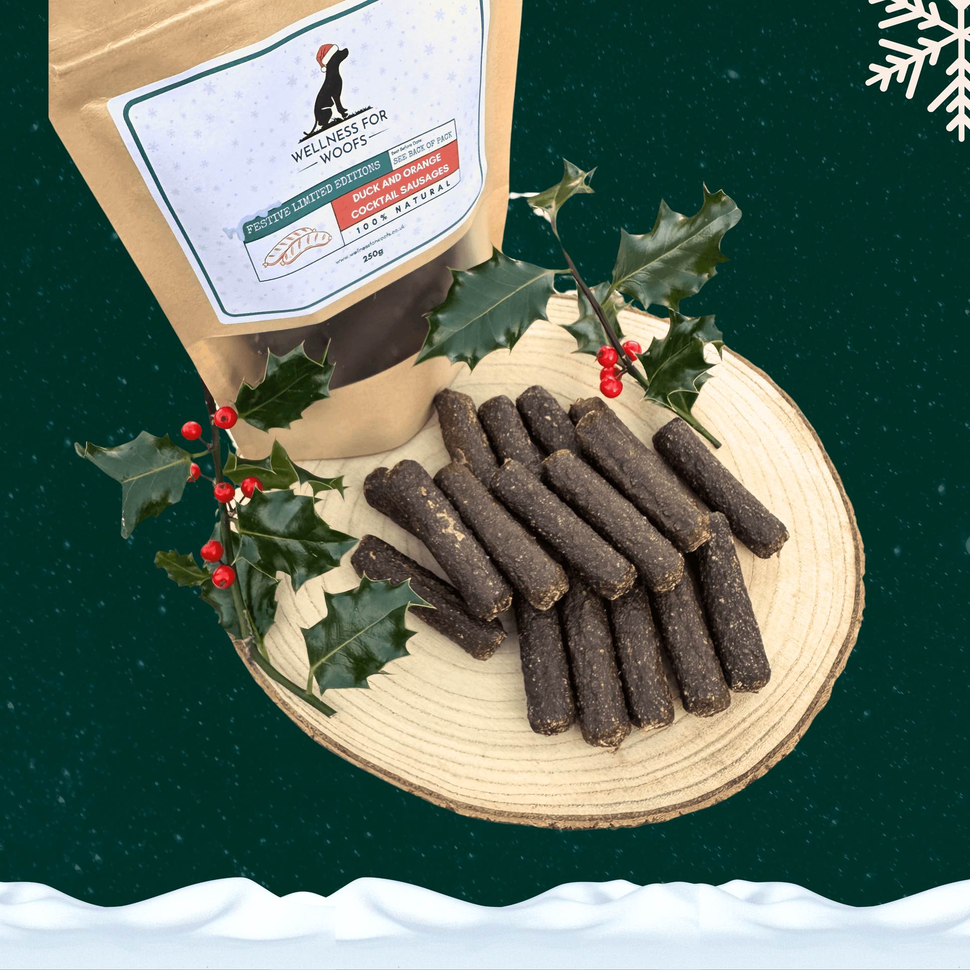 A pile of duck and orange cocktail sausages for dogs in front of a filled pouch of treats and two sprigs of decorative holly. All on a wooden slice plate against a dark green starry sky, with a snowflake in the top right hand corner and a blanket of snow across the bottom.