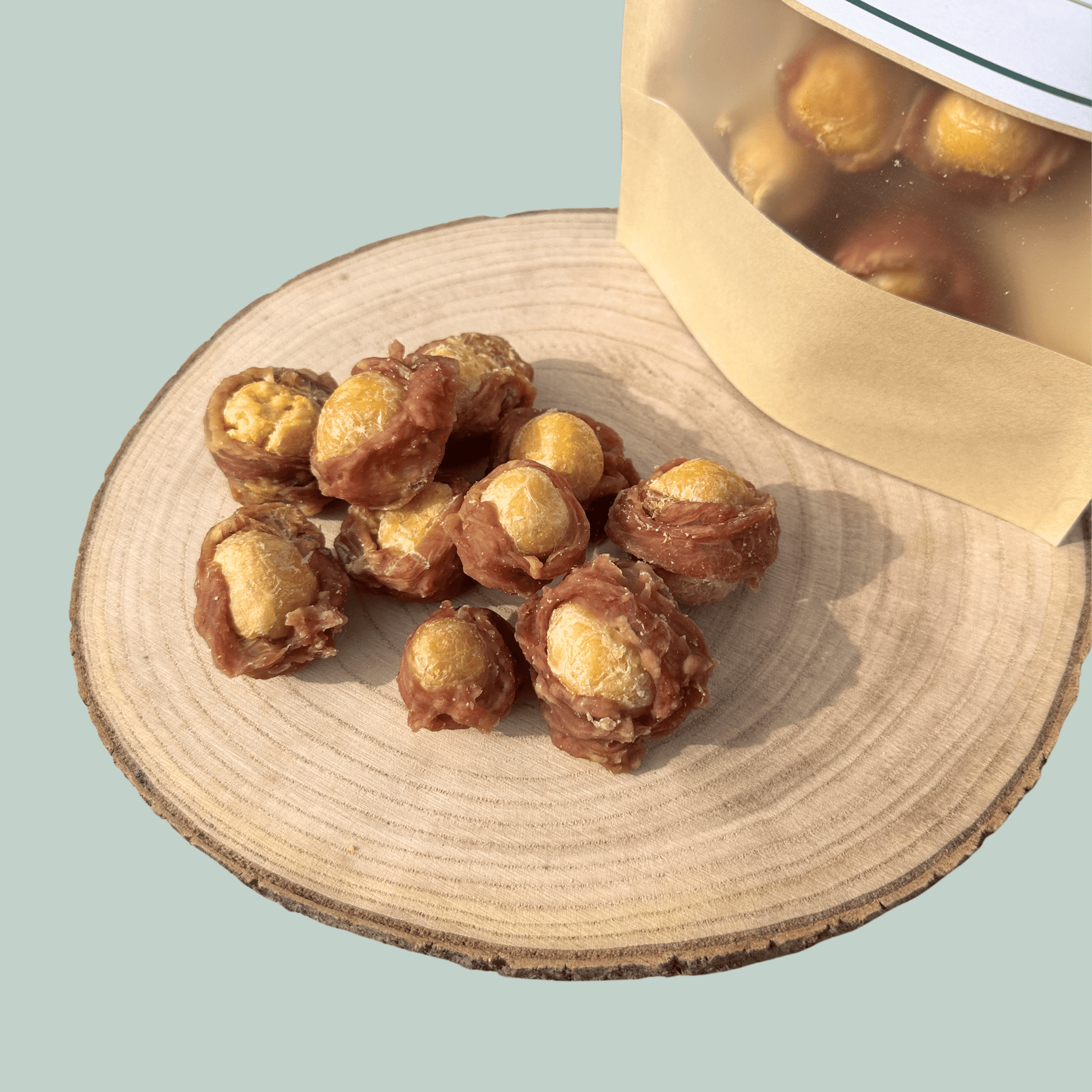 Egg yolks wrapped in dried duck dog treats on a wooden plate in front of a light green background