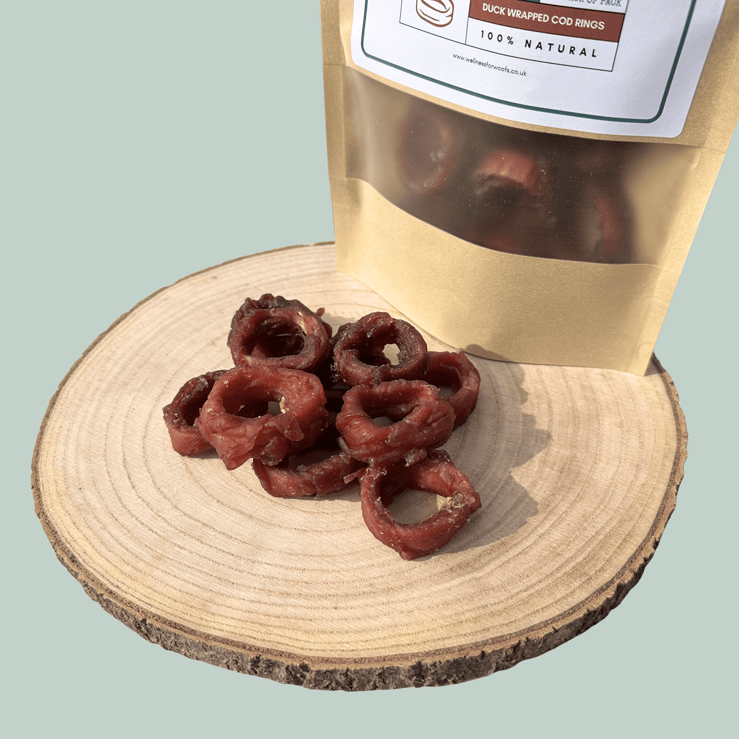 Duck wrapped cod squid rings on a wooden board with a branded packaging bag in the background.