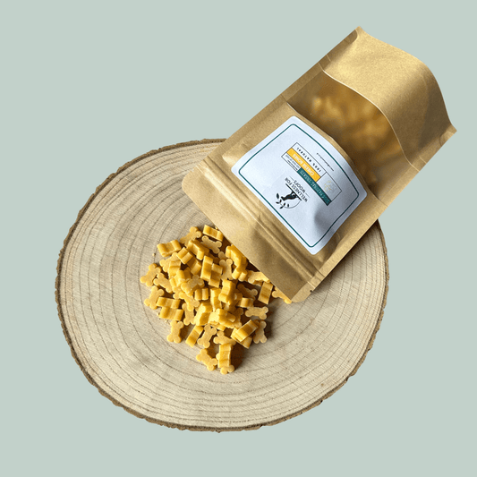 Packaged dog cheese bone treats on a wooden board with a jade green background