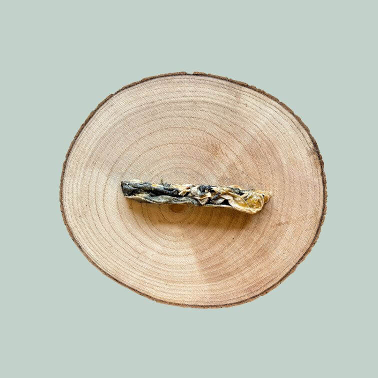 Dried fish finger dog treat on a wooden plate and jade green background