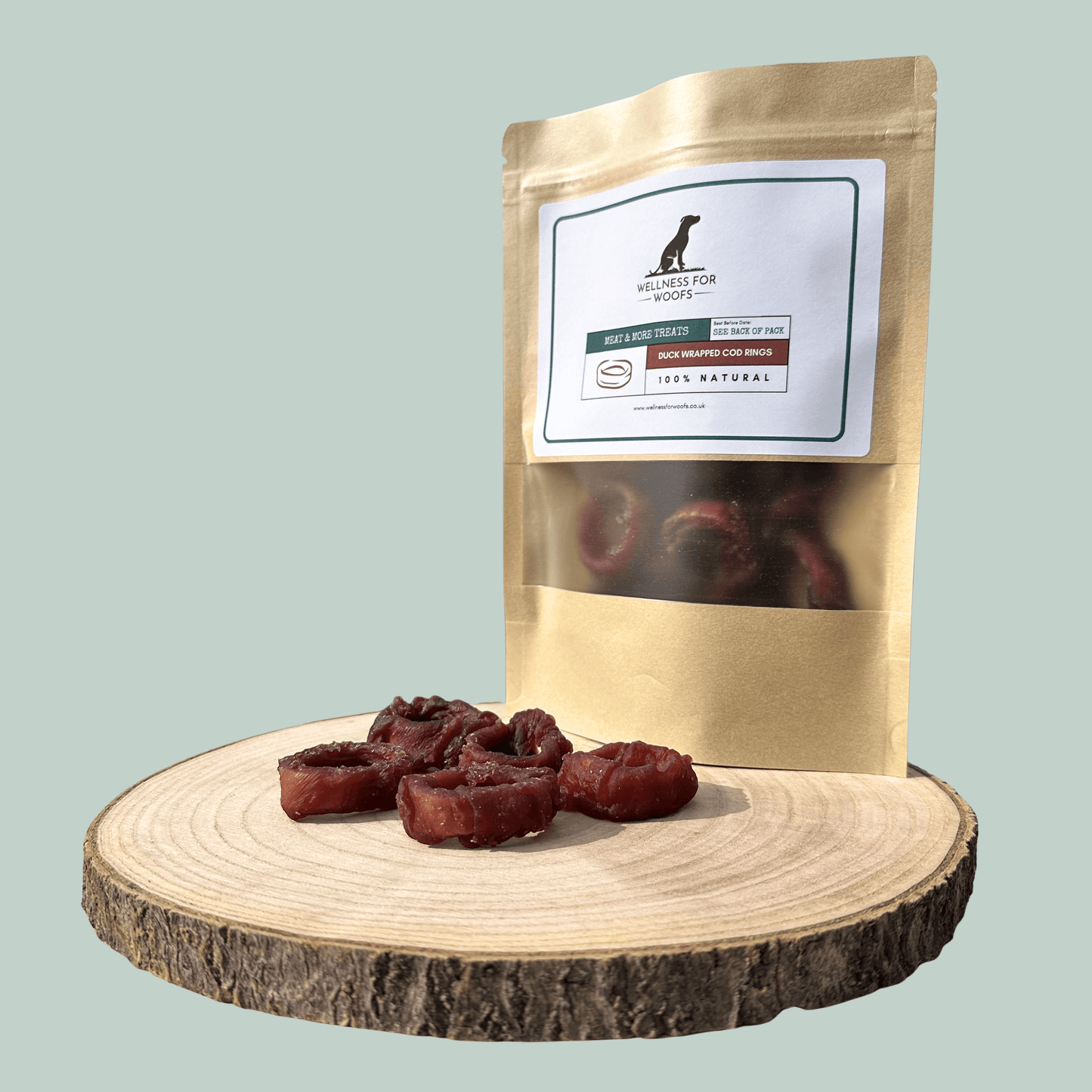 Dog treat package with natural treats on a wooden board against a light green background