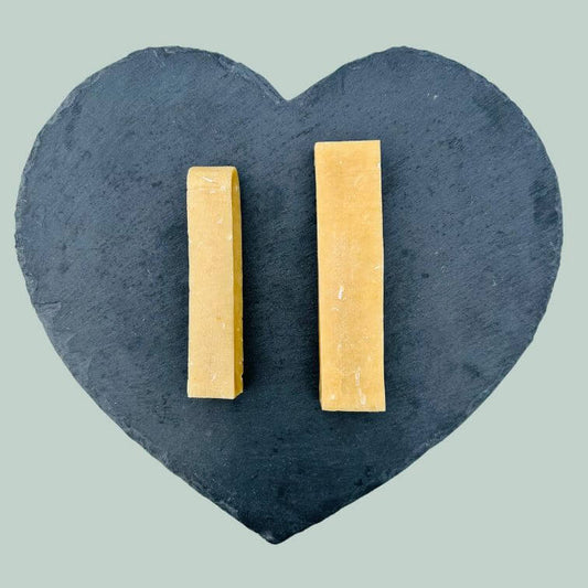 Range of coconut yak bar chews for dogs on a slate plate and jade green background