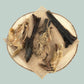 Pieces of dried lamb skin with fur natural dog treats on a wooden plate and jade green background.