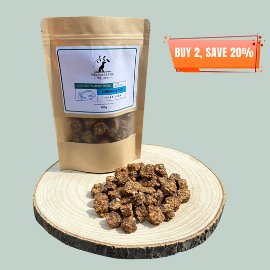 Pouch of herring and cod fish training treats for dogs next to a pile of training treats on a wooden plate