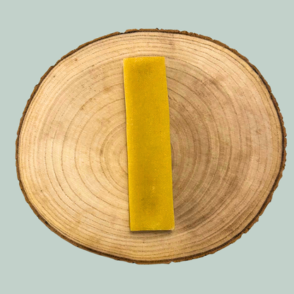 Turmeric flavoured yak bar chew for dogs on a wooden plate against a jade green background.