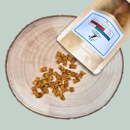 Small pouch of single protein pure turkey dog training treats being emptied on to a wood slab plate. 