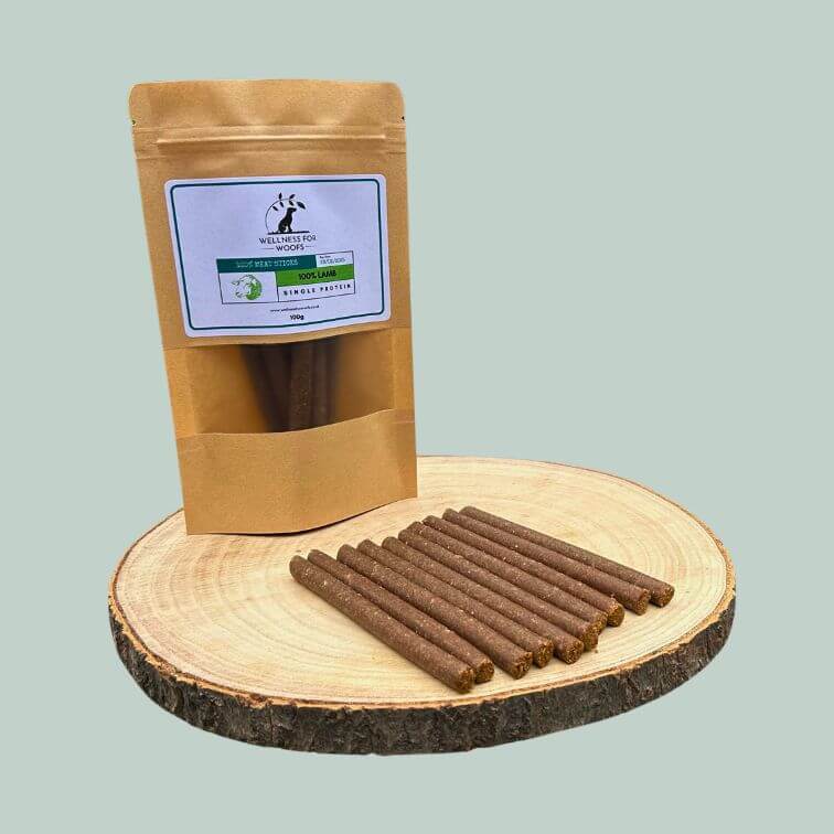 Pack of lamb meat sticks for dogs on a wooden plate