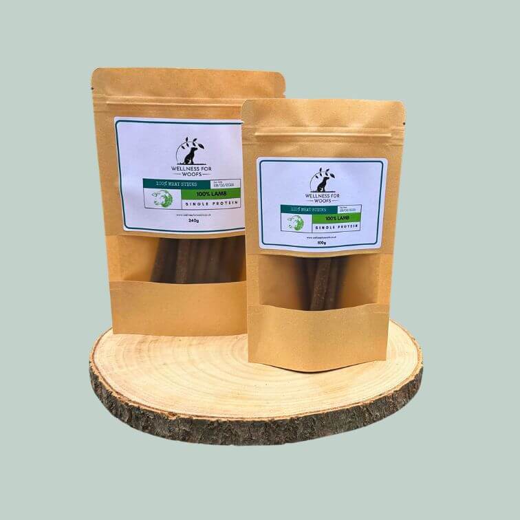 Two packs of lamb meat sticks for dogs on a wooden plate