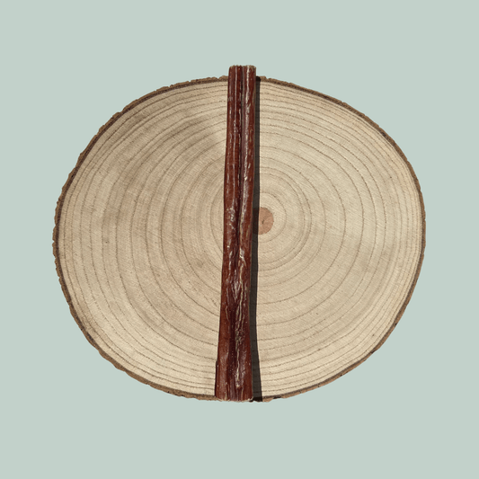 Long pizzle for dogs on a wood slice plate against a jade green background