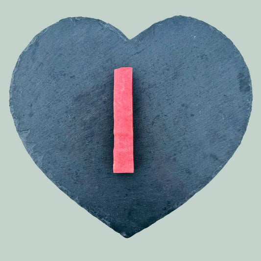 Medium strawberry yak bar for dogs on a slate plate and jade green background