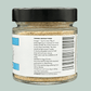 A glass jar with a black lid containing organic psyllium husks for dogs. The label is blue and white and provides feeding instructions for dogs.