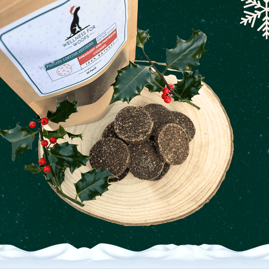 Pile of pheasant and partridge cookies for dogs on a wooden slice plate next to a filled pouch of 10 cookies. All on a starry green background with a white snowflake in the top right hand corner and a blanket of snow across the bottom.