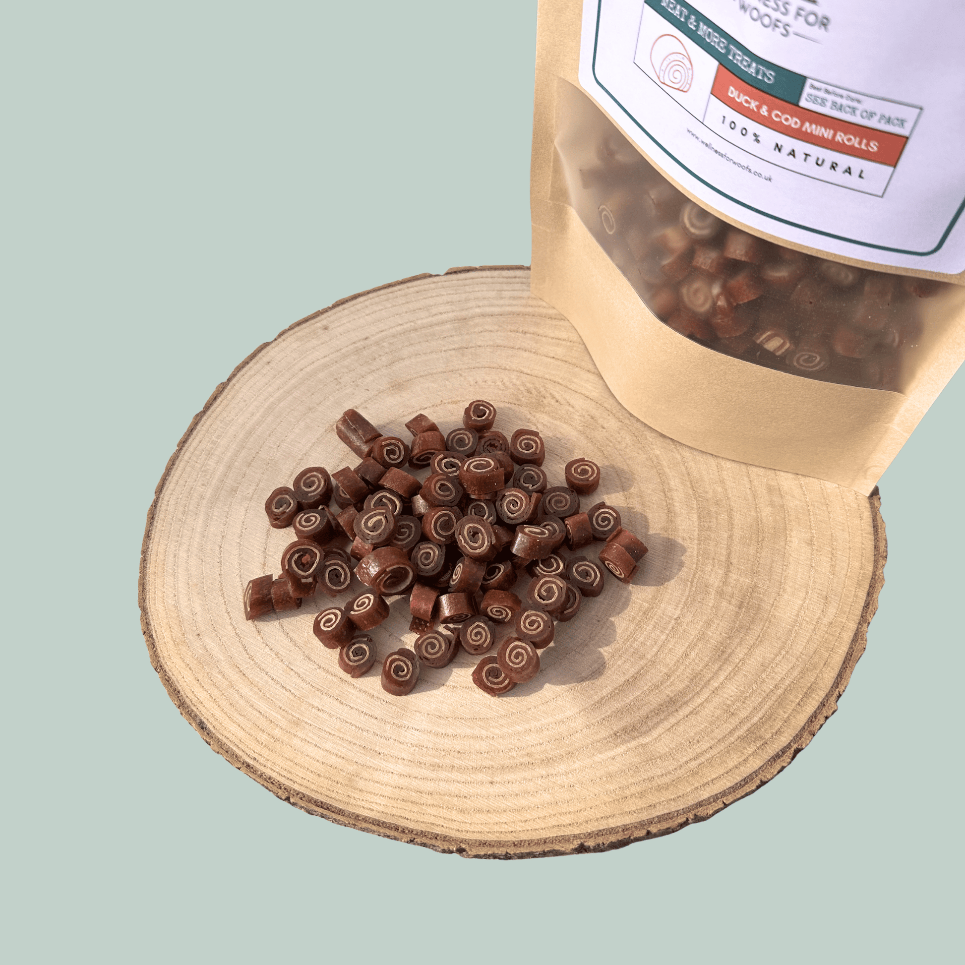 Pile of duck and cod training treats for dogs on a wooden plate with a eco-friendly pouch.