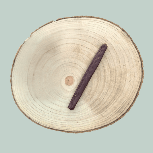 A single guinea fowl sausage dog treat on a wooden plate.