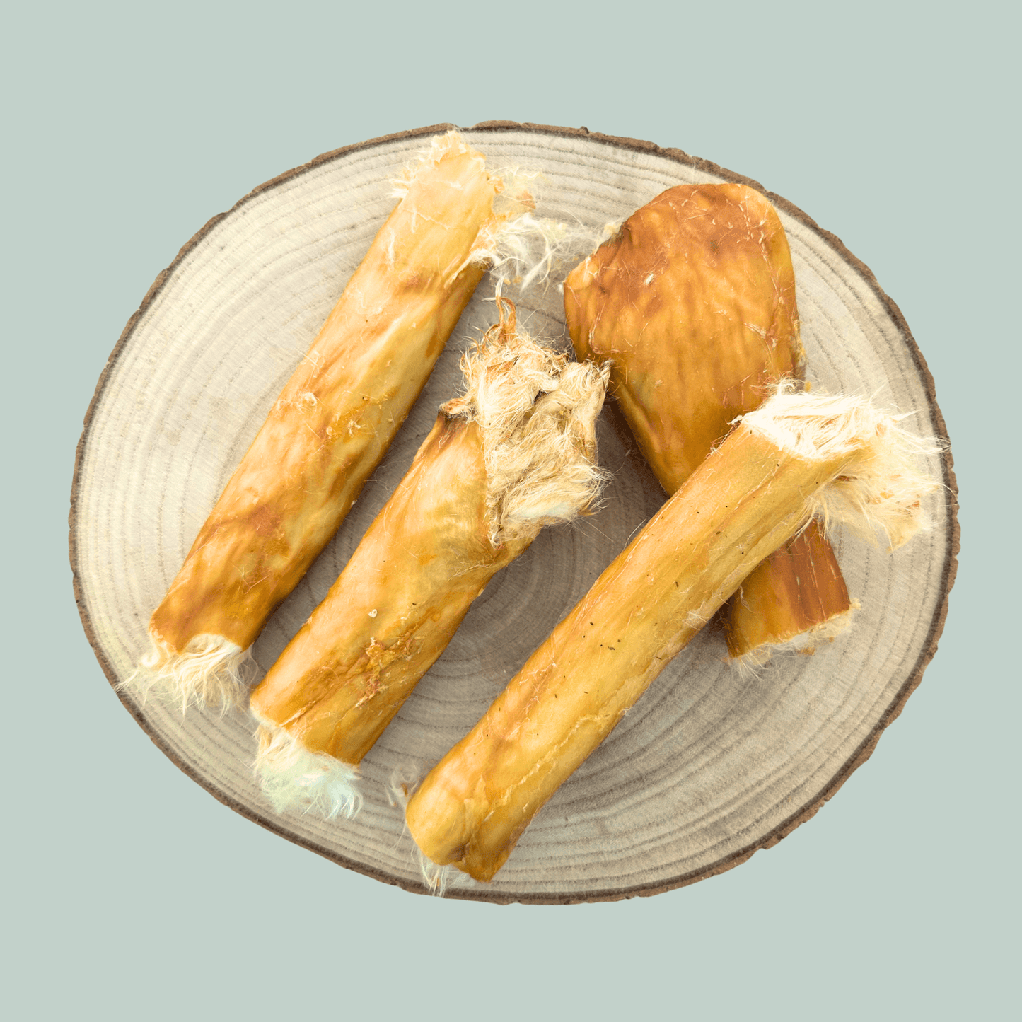 Plate of 4 rabbit skin roll natural dog chews against a jade green background.