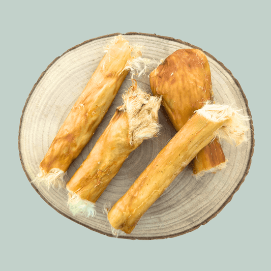 Plate of 4 rabbit skin roll natural dog chews against a jade green background.