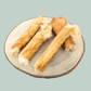 4 rolls of dried furry rabbit skin on a wood slice plate against a jade green background.