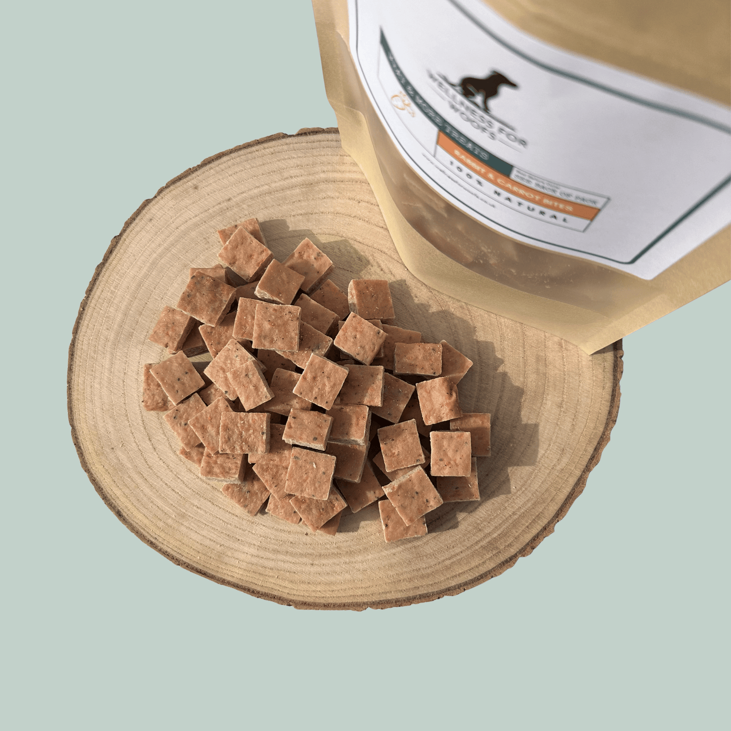 Dog treats on a wooden surface with a pet food container in the background