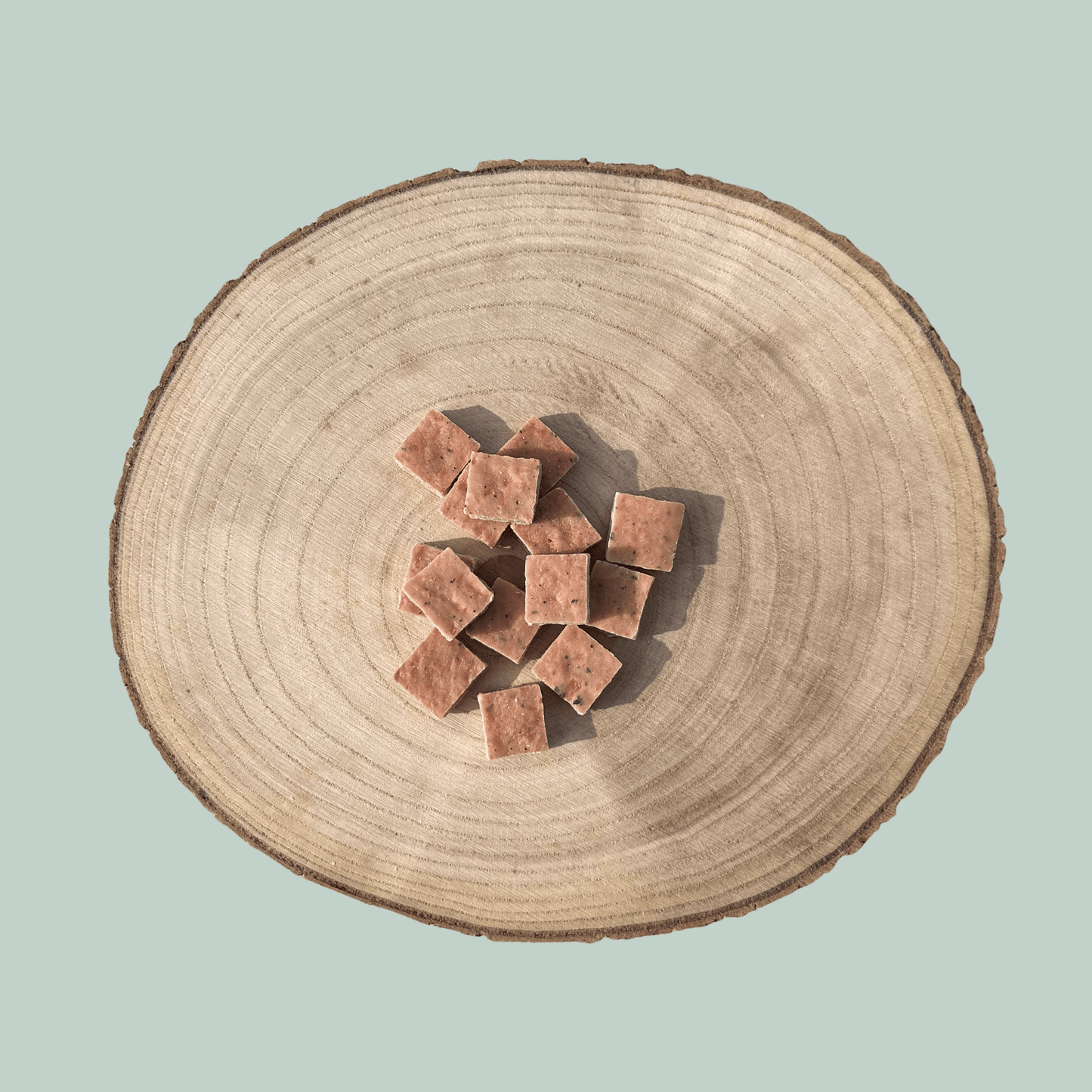 Wooden log with square-shaped dog treats on a light blue background