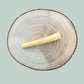 Single buffalo tail piece natural dog chew for dogs on a wooden slice plate against a jade green background.