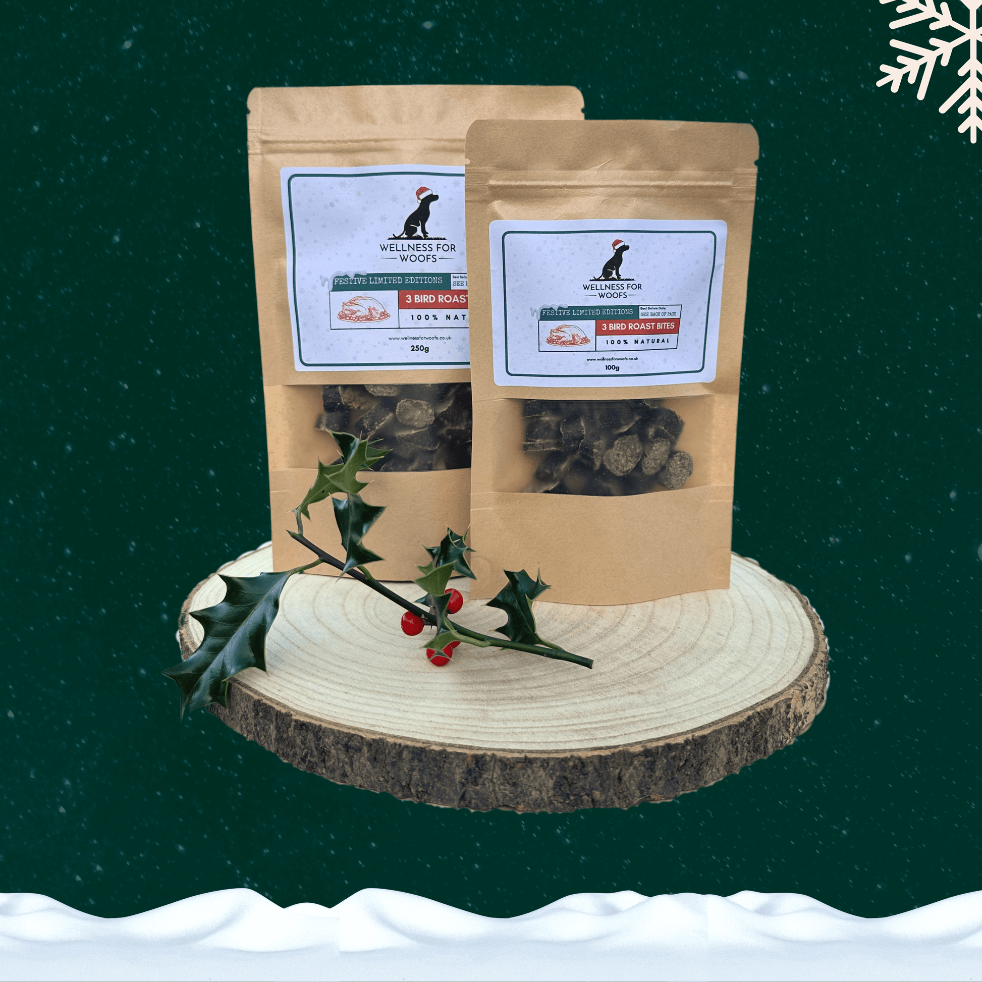 Two pouches of sausage slice dog treats on a wooden plate, standing behind a sprig of holly. All set against a dark green starry sky background with a snowflake in the top right hand corner and a blanket of snow across the bottom.