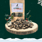 A large pile of 3 bird sausage slices for dogs on a wooden slice plate. Behind the pile stands a pouch full of dog treats and two sprigs of decorative holly. The plate and pouch stand against a dark green starry sky background with a snowflake in the top right hand corner and a blanket of snow across the bottom.