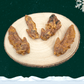 4 dried turkey wing dog chews on a wooden slice plate against a dark green starry background with a white snowflake in the top right corner and a blanket of snow across the bottom.