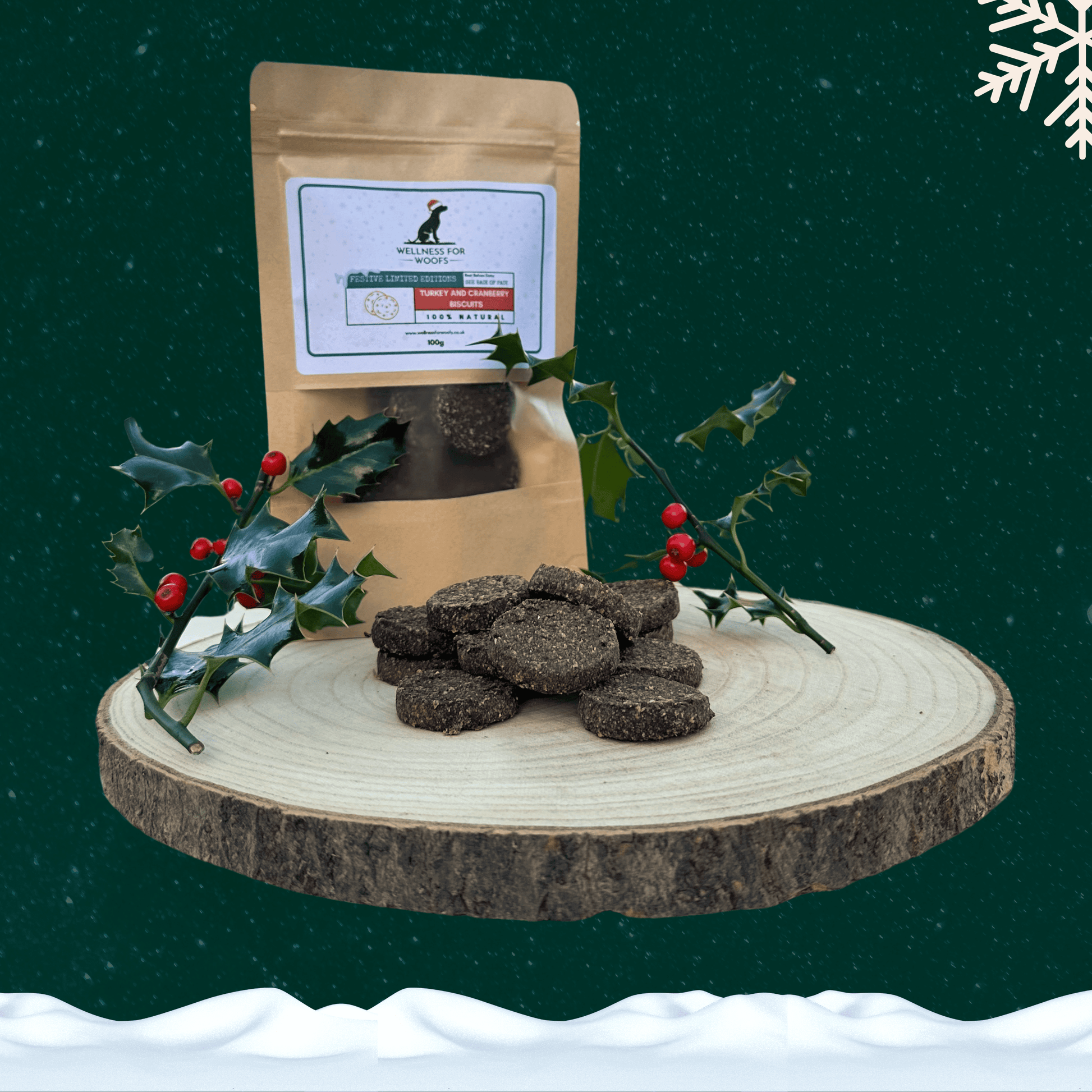 Pile of Turkey and Cranberry Biscuits for dogs on a wooden plate next to a pouch full of treats and two sprigs of holly. All set on a dark green starry background with a white snowflake in the top right corner and a blanket of snow across the bottom.