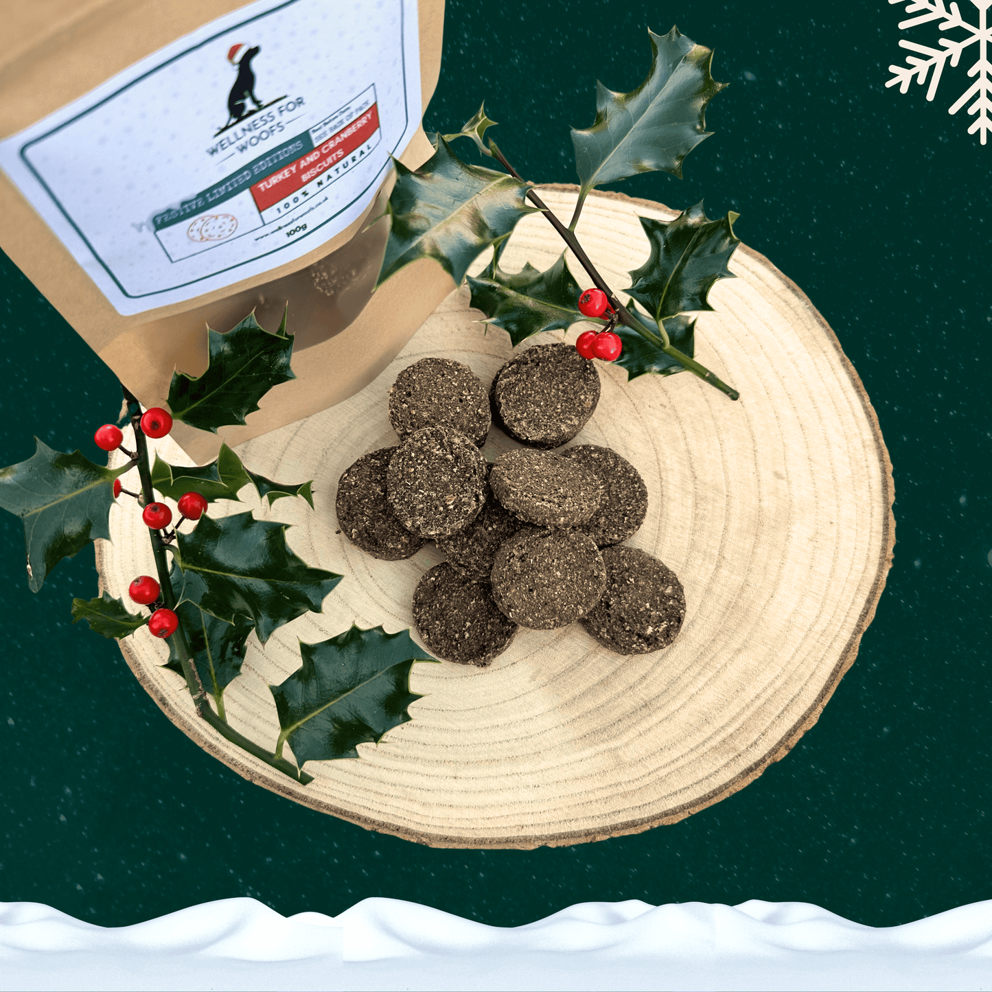 Pile of Turkey and Cranberry Biscuits for dogs on a wooden plate next to a pouch full of treats and two sprigs of holly. All set on a dark green starry background with a white snowflake in the top right corner and a blanket of snow across the bottom.