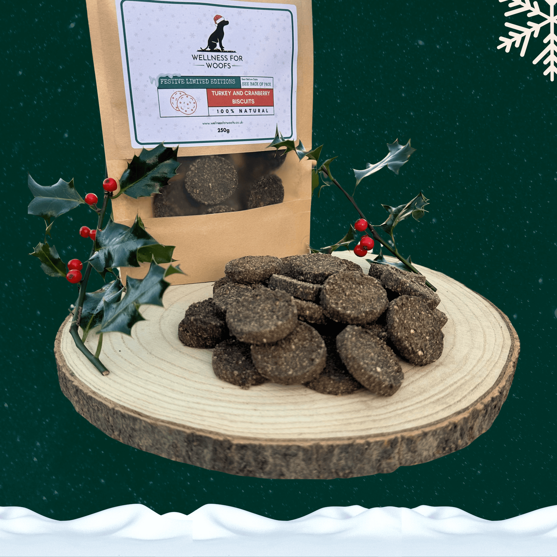 Pile of Turkey and Cranberry Biscuits for dogs on a wooden plate next to a pouch full of treats and two sprigs of holly. All set on a dark green starry background with a white snowflake in the top right corner and a blanket of snow across the bottom.