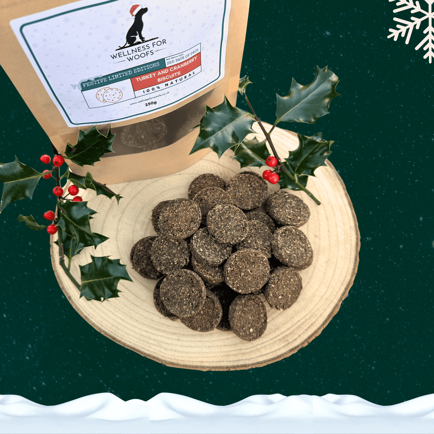 Pile of Turkey and Cranberry Biscuits for dogs on a wooden plate next to a pouch full of treats and two sprigs of holly. All set on a dark green starry background with a white snowflake in the top right corner and a blanket of snow across the bottom.