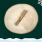 A slice of venison skin chew for dogs on a wooden plate against a dark green starry sky background. There is a white snowflake in the top right corner and a blanket of snow across the bottom.