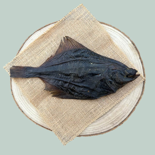 Whole dried flounder dog chew on a wooden plate