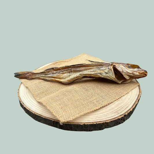 Dried haddock fish treat for dogs on a wooden plate