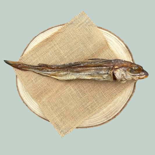 Dried haddock fish dog treat on a wooden plate